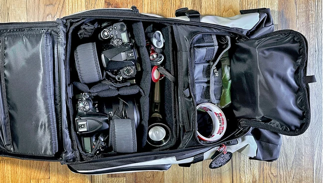 Professional camera backpack with organized gear compartments containing cameras, lenses, and photography accessories.