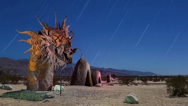 Large ornate wooden dragon sculpture in desert landscape with star trails visible in night sky
