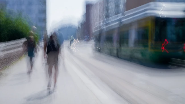 Blurred urban street scene with pedestrians and passing transit bus