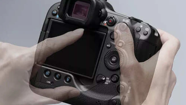 Photographer holding professional DSLR camera from behind, displaying rear LCD screen and control layout