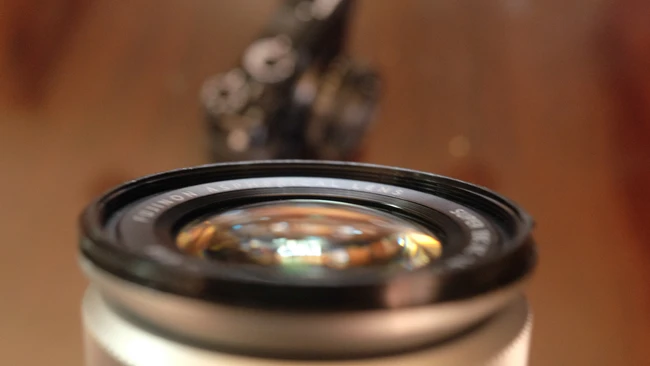 Close-up of a camera lens with shallow depth of field, showing glass elements and black barrel