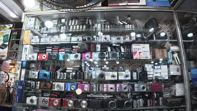 Extensive display of compact digital cameras organized in glass display case