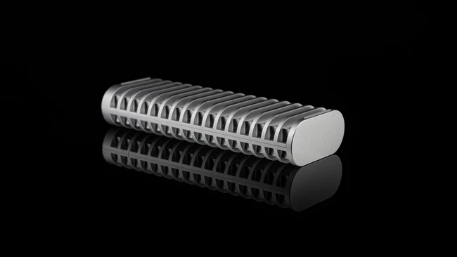 Close-up product shot of a cylindrical metal component with deep linear grooves along its surface