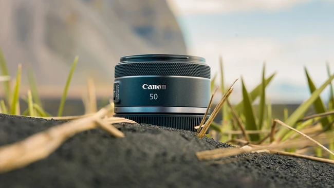 Canon RF 50mm lens positioned on textured ground with shallow depth of field