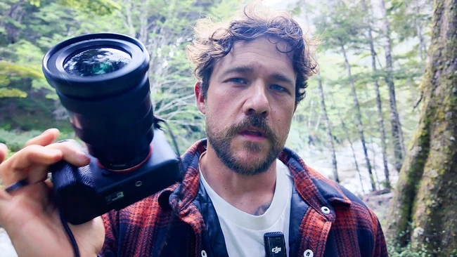 Photographer holding a wide-angle lens outdoors in a forest setting