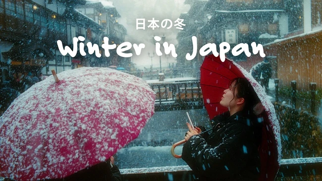 Person holding red umbrella in heavy snowfall on urban street with Japanese text overlay