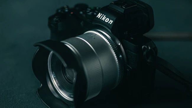 Nikon mirrorless camera with attached prime lens on dark teal surface