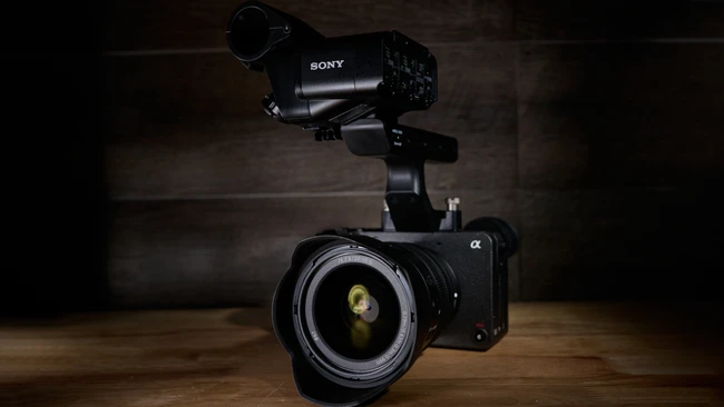 Sony mirrorless camera with telephoto lens and external microphone mounted on wooden surface