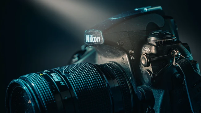 Nikon D70 DSLR camera with telephoto lens against dark background with blue-tinted dramatic lighting