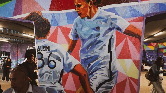 Large-scale mural of female athlete in dynamic pose with geometric background pattern
