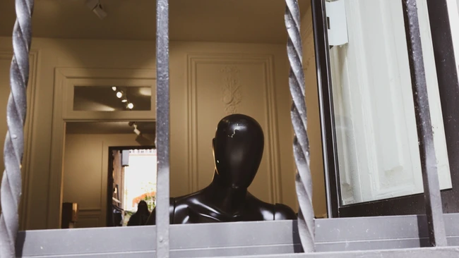 Black mannequin head displayed in storefront window behind white frames