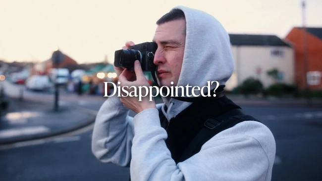 Person in white hoodie holding film camera to face with 'Disappointed?' text overlay