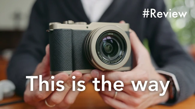 Person holding a mirrorless camera with a fixed prime lens, displayed for review