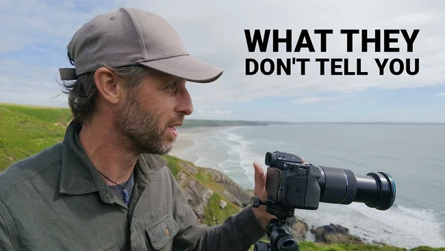 Photographer with telephoto lens on tripod overlooking coastal cliffs and ocean waves