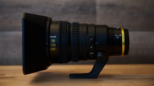 Nikon 28-135mm cinema lens with hood and support bracket on wooden surface