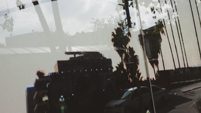 Double exposure of silhouetted buildings and palm trees overlaid with cloudy sky