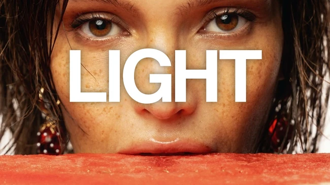 Close-up portrait of woman's face with word 'LIGHT' overlaid in white typography