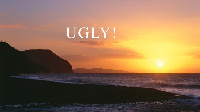 Dramatic golden sunset over a dark beach with rocky headland silhouettes