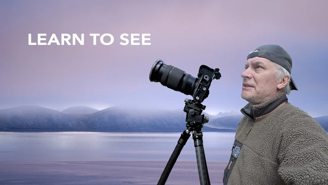 Photographer with telephoto lens on tripod overlooking misty lake landscape at dawn