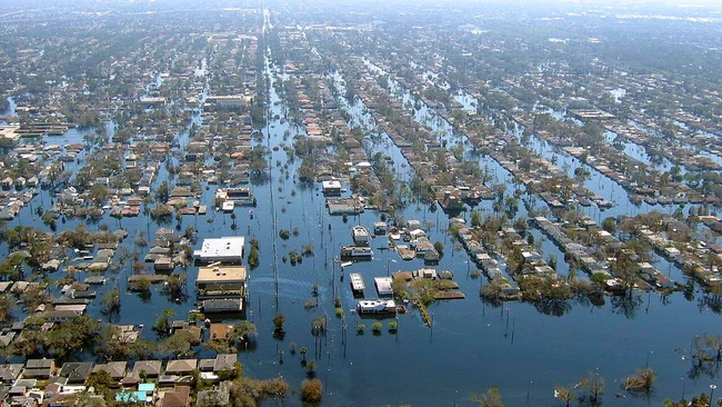 Aerial view of a residential neighborhood largely submerged in floodwater, with rooftops and treetops rising above the water