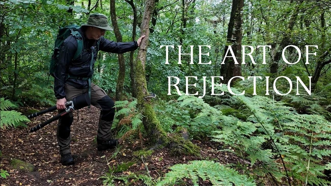 Hiker on forest trail with text overlay reading 'The Art of Rejection'