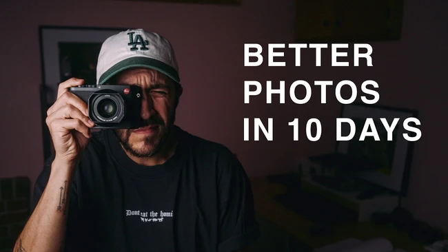 Photographer holding vintage film camera wearing LA Dodgers cap against dark interior backdrop