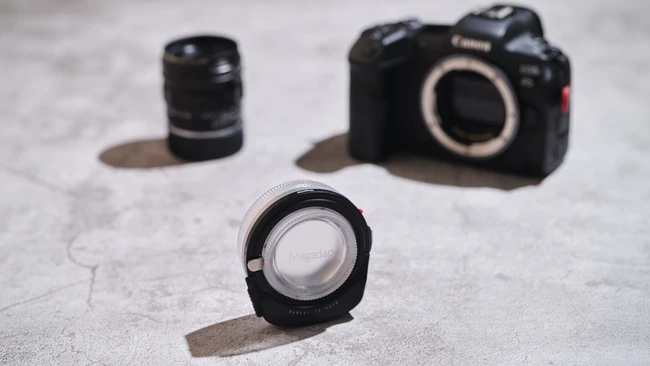 Canon R5 mirrorless camera body and three Canon RF lenses arranged on concrete surface
