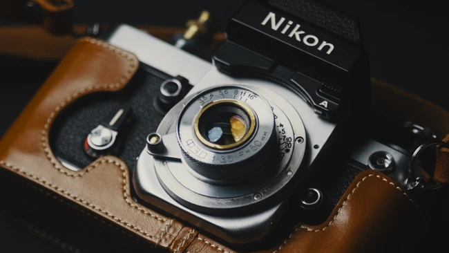 Nikon film camera with brown leather case and vintage lens detail