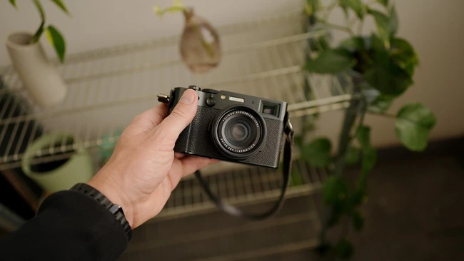 Hand holding a vintage rangefinder camera with black body and silver lens