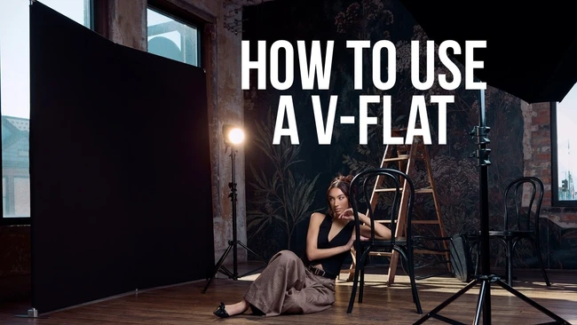 Studio portrait setup with woman seated on ladder beside professional lighting equipment and black v-flat reflector