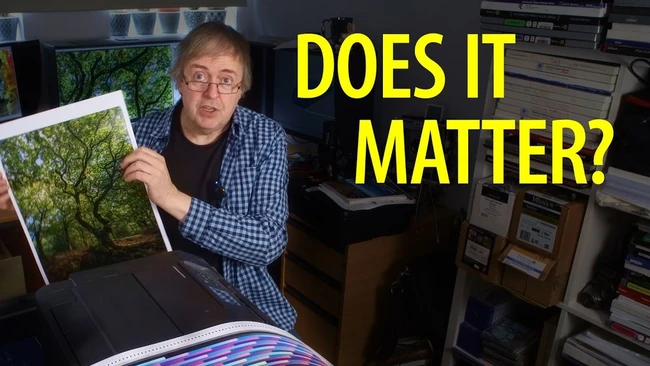 Man holding framed landscape print next to color-managed monitor in studio setting