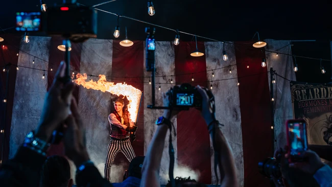 Fire breather performer on stage with audience members recording on phones