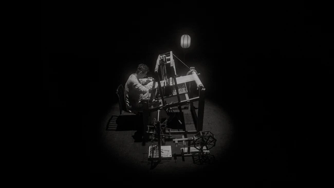 Cinematographer operating a film camera on a crane rig in dramatic studio lighting