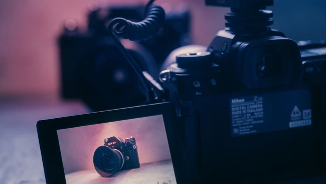 Digital camera displayed on monitor screen with camera equipment and lighting setup in background