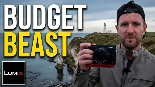 Man holding Lumix camera against coastal cliff landscape with lighthouse