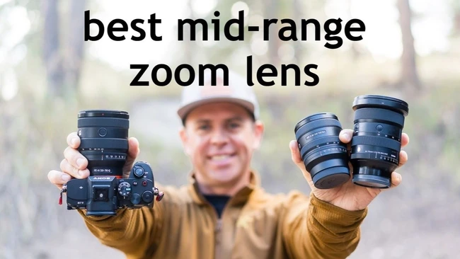 Smiling man in a white cap and tan jacket holding up a mirrorless camera with a zoom lens and two other lenses outdoors, with the text 'best mid-range zoom lens'.