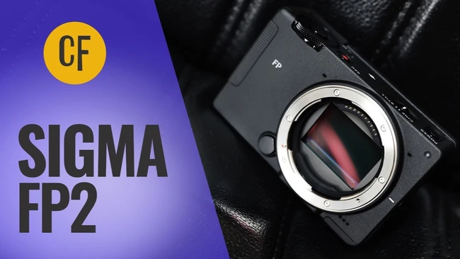 Video thumbnail for the Sigma FP2 camera, showing the black compact body with its exposed sensor on black leather, beside bold white text.