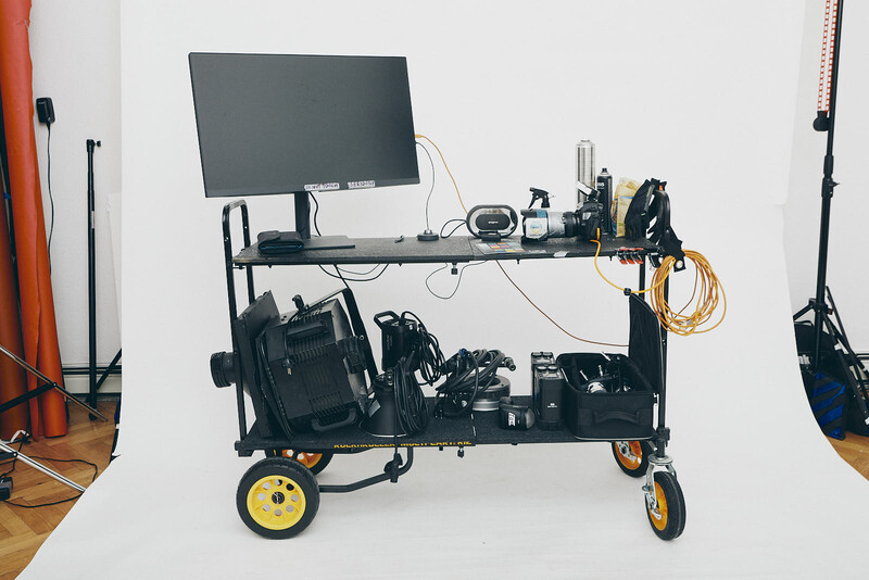 Mobile production cart with monitor, camera equipment, and storage on yellow-wheeled platform.