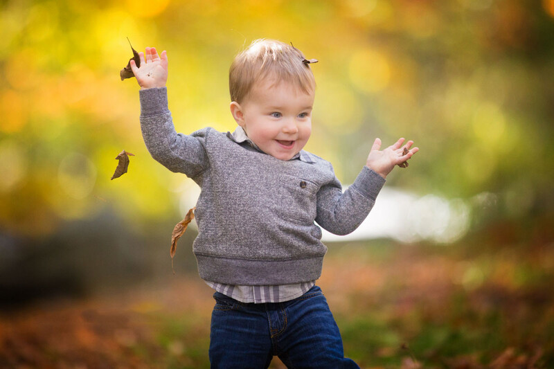 happy boy tossing leaves in the fall