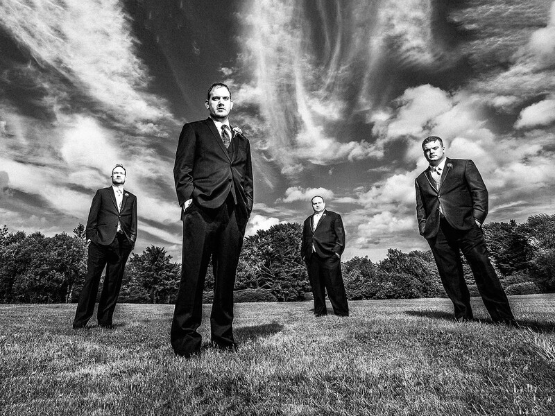 four groomsmen standing in field