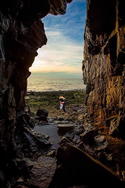 engaged couple on beach photographed from cave