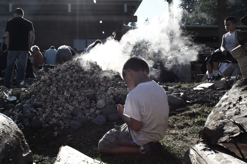 Young boy helps his tribe cook clams in the traditional way. 