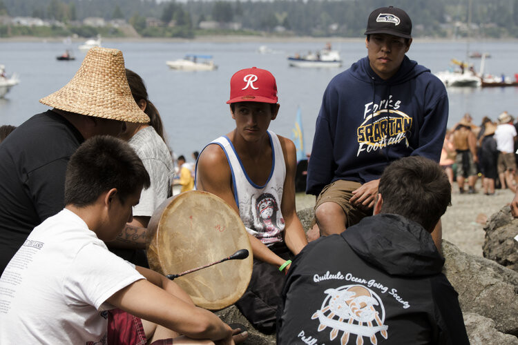 A group of young men singing traditional songs together beside the water. Photo by Gabrielle Colton.