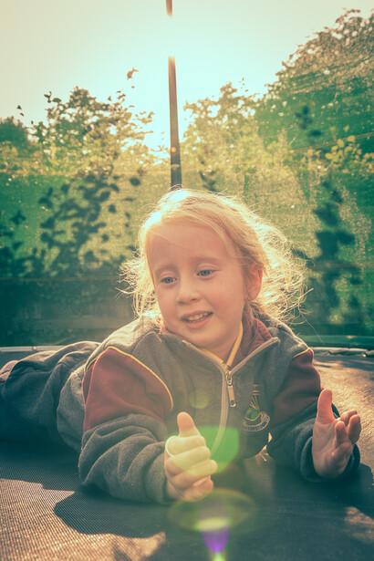 little girl on trampoline. photograph of girl lying on trampoline. candid portrait of child.
