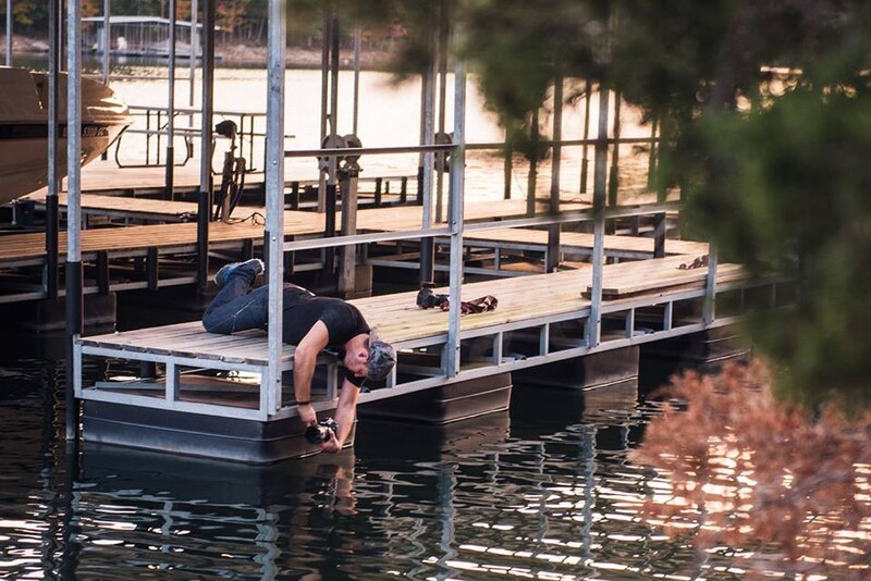 Behind the scenes of Jason Vinson hanging over water with his camera to get a low angle 