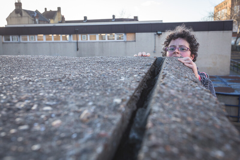 A female parkour athlete climbing up a concrete wall. Andy Day.