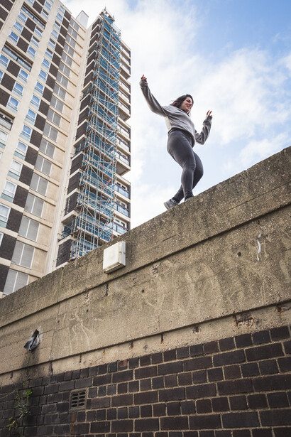 A female parkour athelte running along the top of a wall. Andy Day.