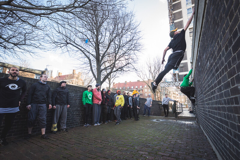 A parkour athlete jumping to grab the top of a wall. Andy Day.