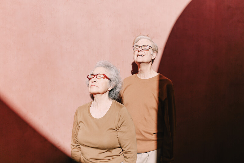 Elderly couple leaning against a wall.