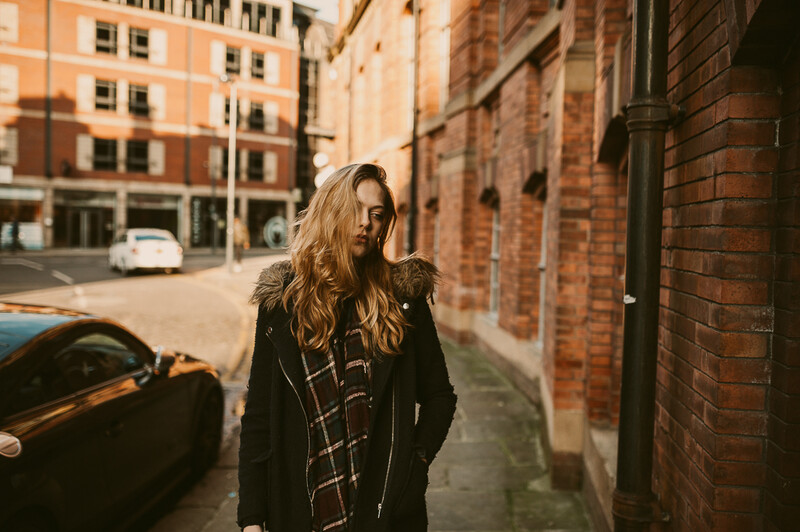 Young blond woman walking down a street.